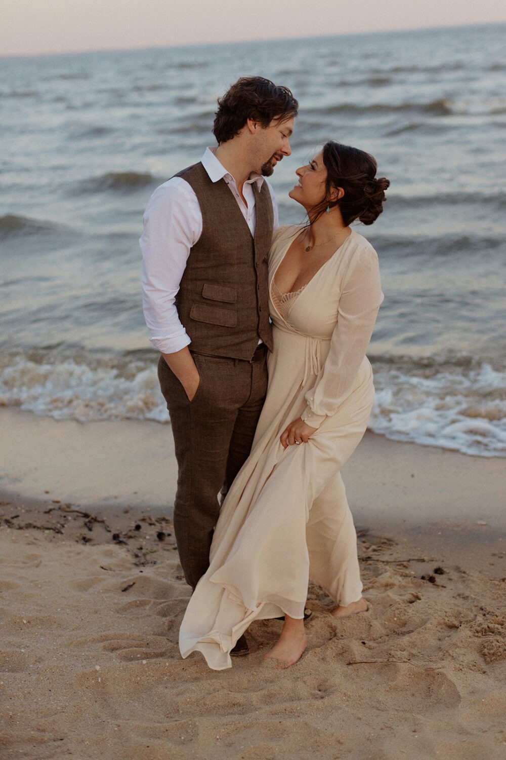 couple embraces in sand at beach engagement session