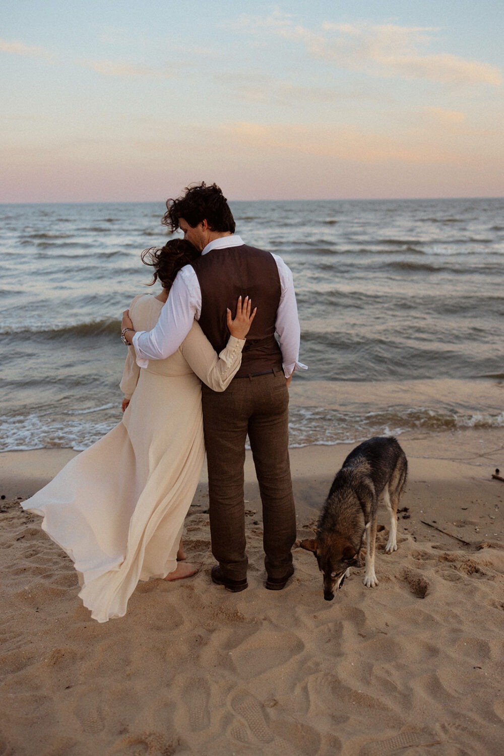 couple embraces in sand at beach engagement session