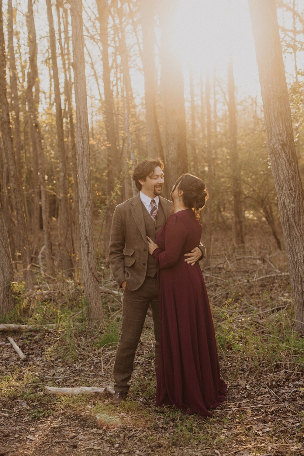 couple embraces in sunset woods engagement session