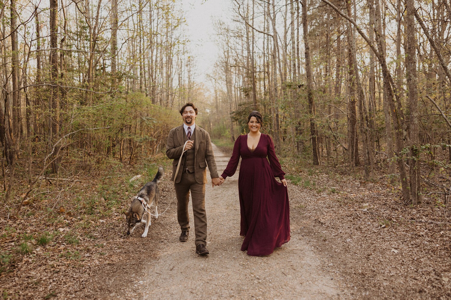 couple walks through woods with dog