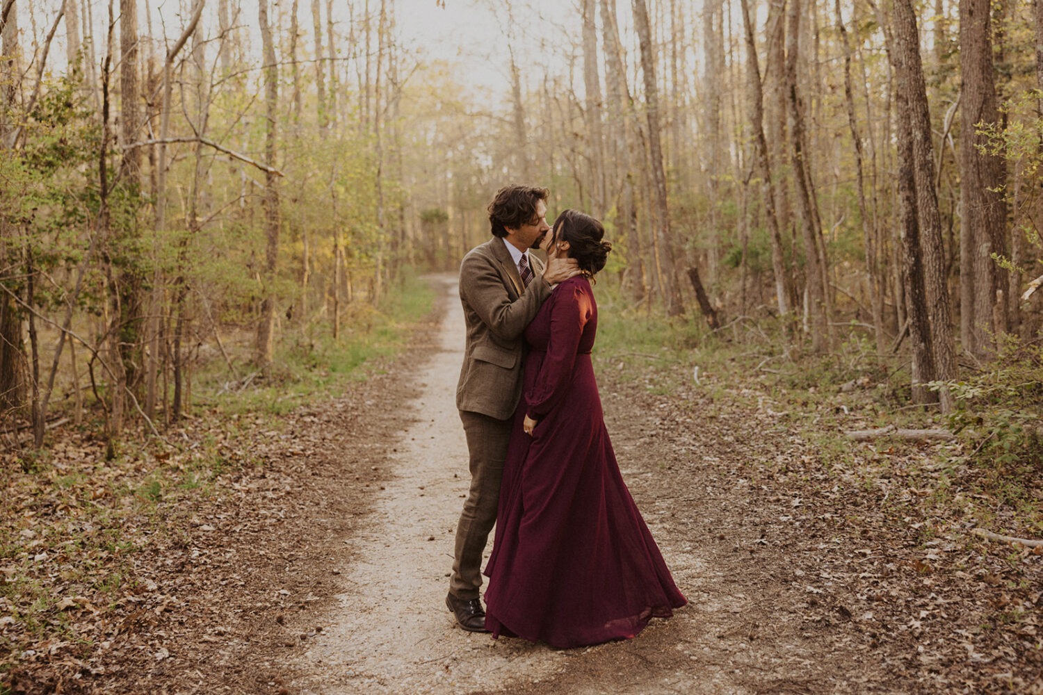 couple kisses in woods at sunset engagement session