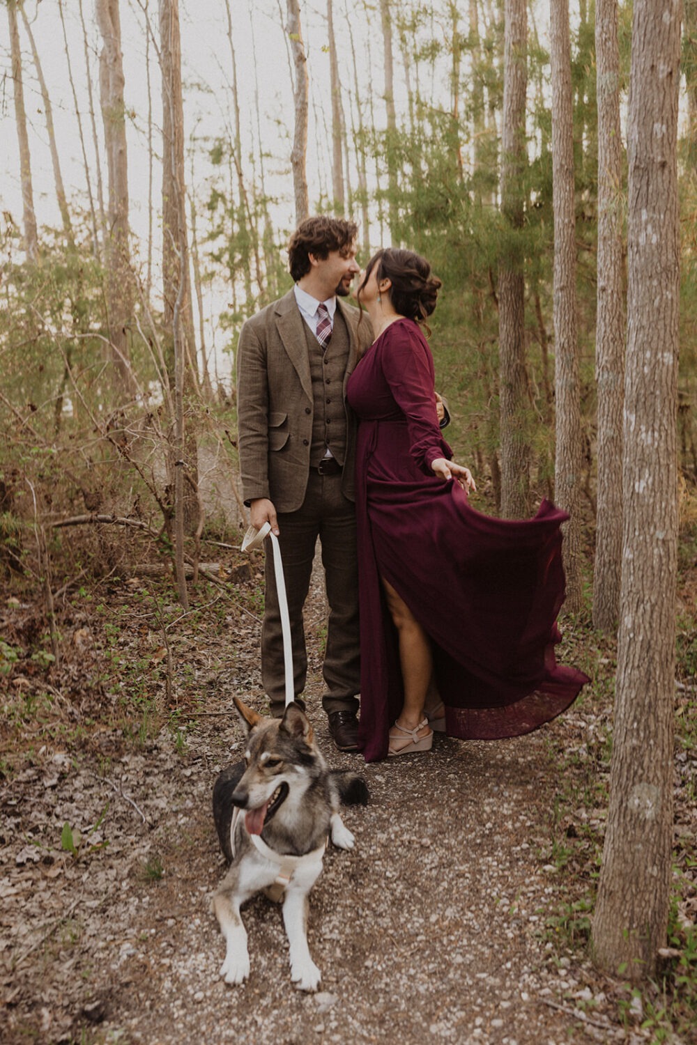 couple poses with dog at outdoor couples shoot