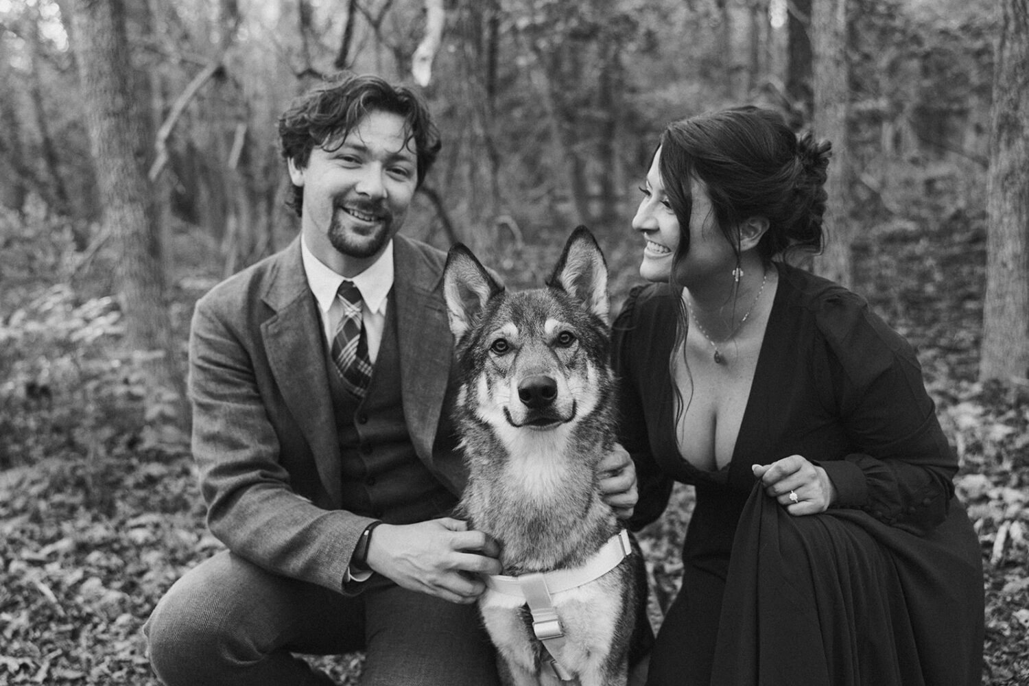 couple poses with dog at woods shoot