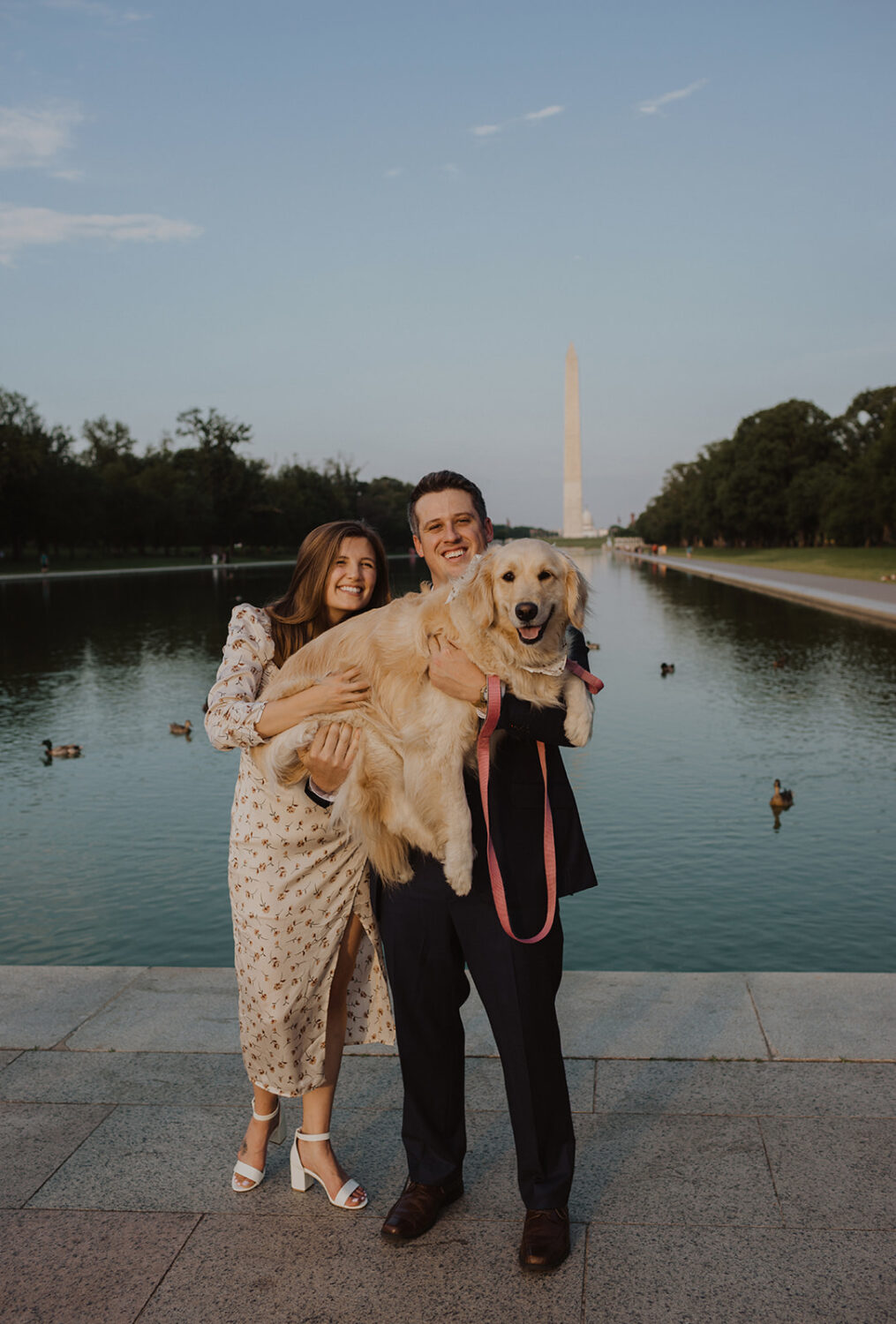 couple holds dog at sunset Lincoln Memorial engagement session