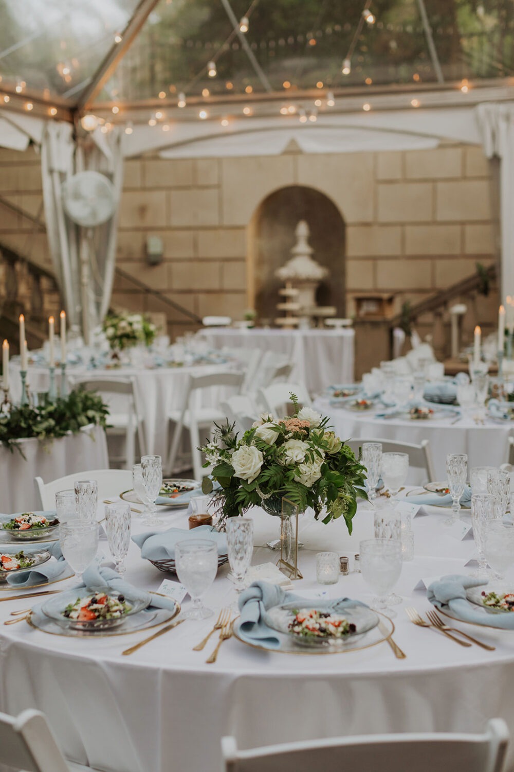 blue and gold table settings at tent garden wedding