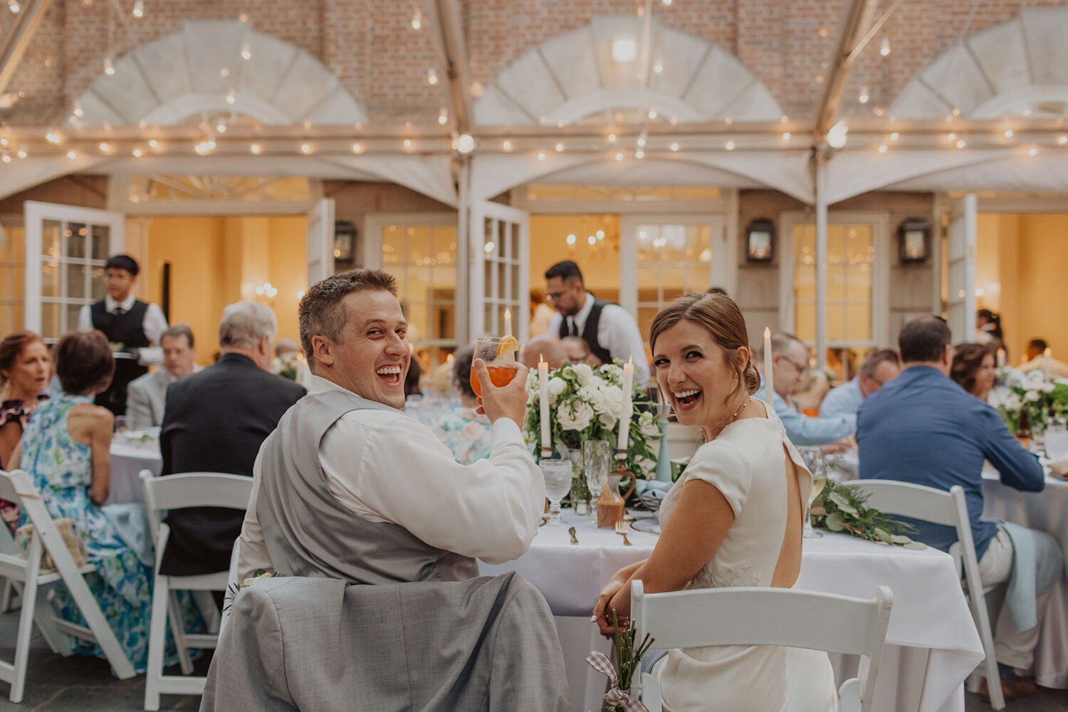 couple laughs at tented wedding reception