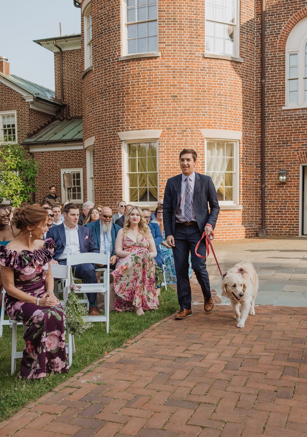 groomsman walks dog down aisle at garden wedding 