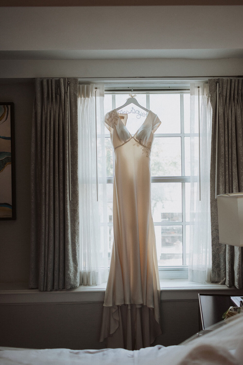 white wedding dress hangs on window