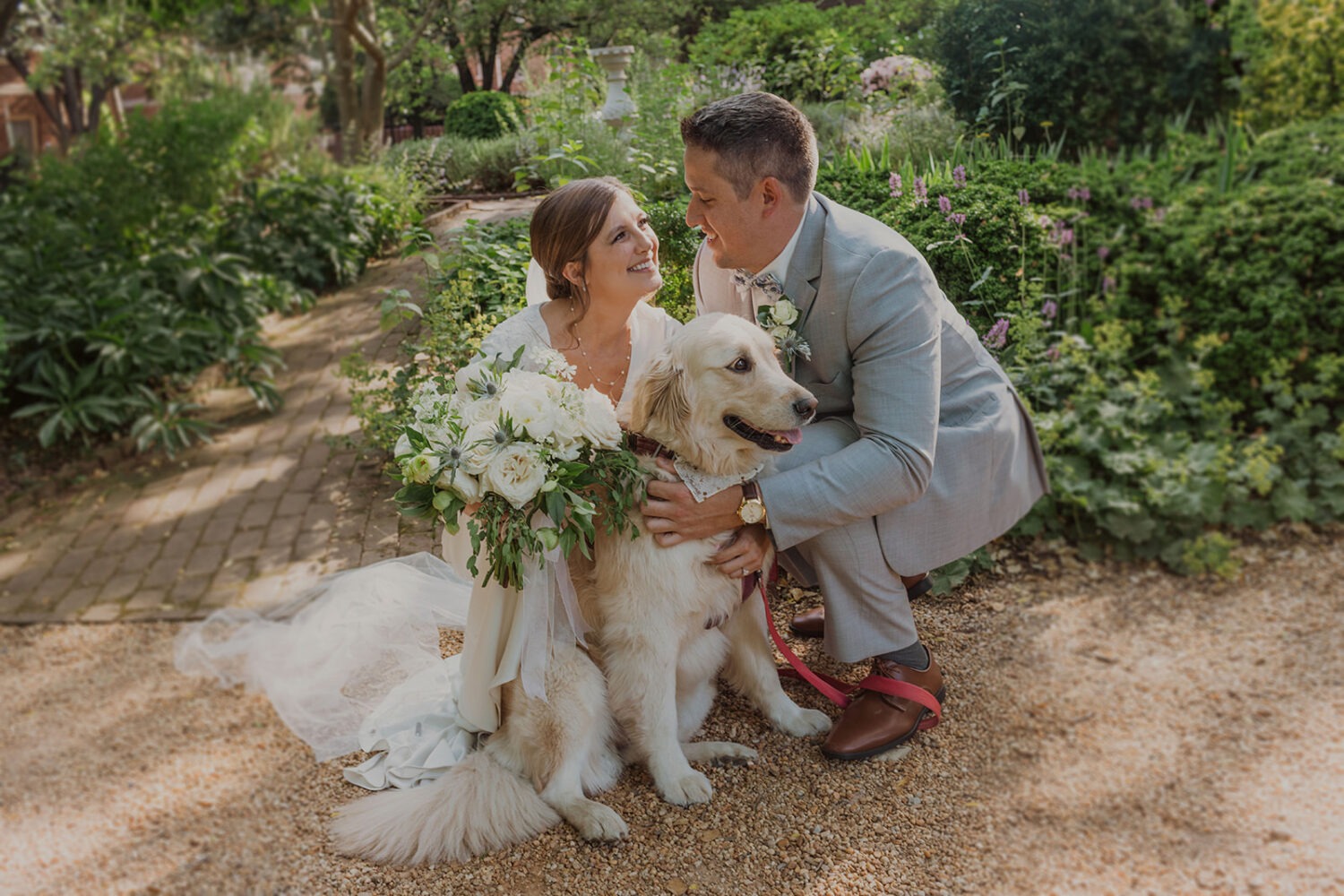 couple hugs pet dog at garden wedding