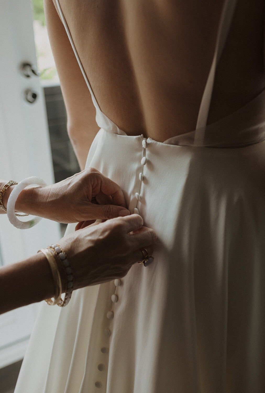 bride has dress buttoned during wedding getting ready 