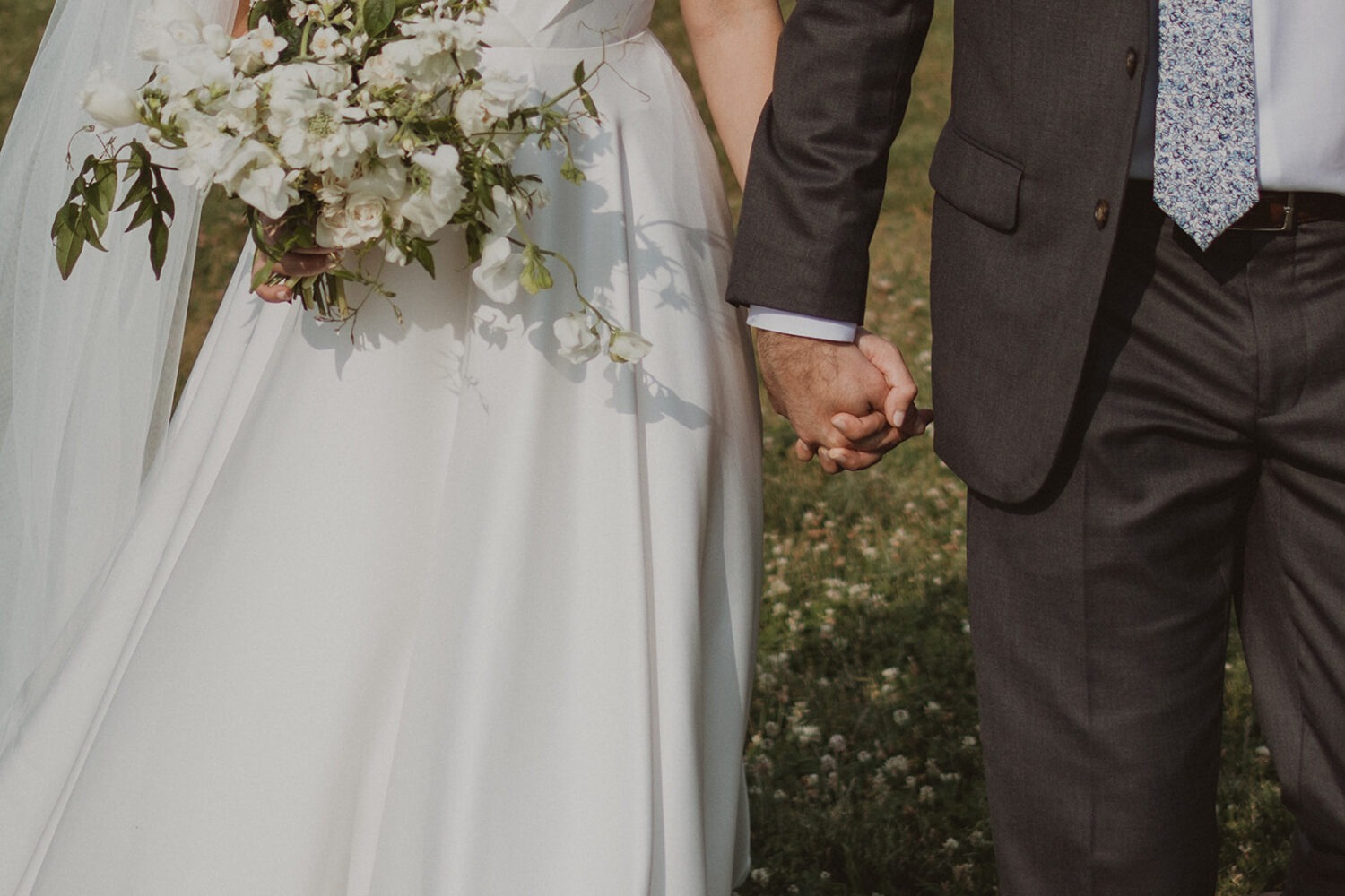 couple holds hands in sunset meadow