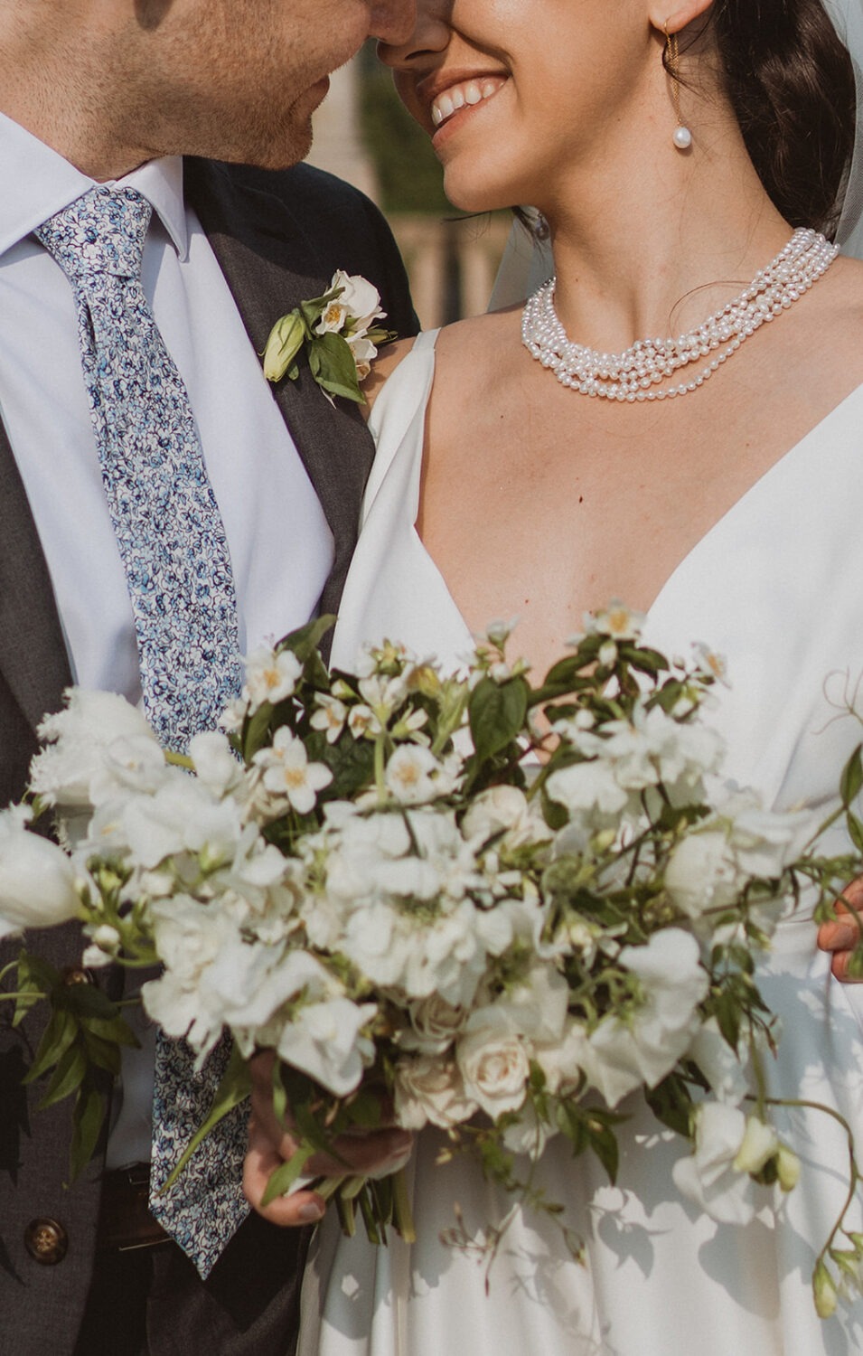 couple embraces holding white wedding bouquet 