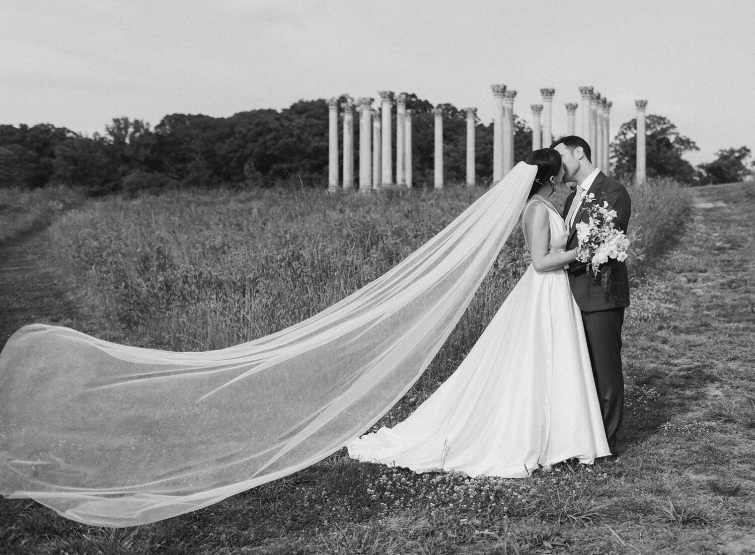 couple kisses in front of Capitol Columns at National Arboretum DC