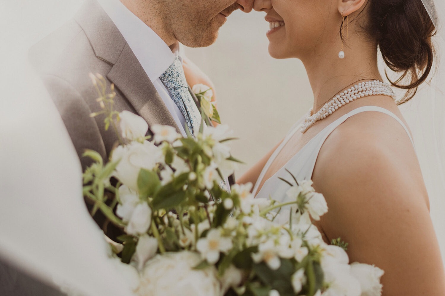 couple embraces with white wedding bouquet under veil 