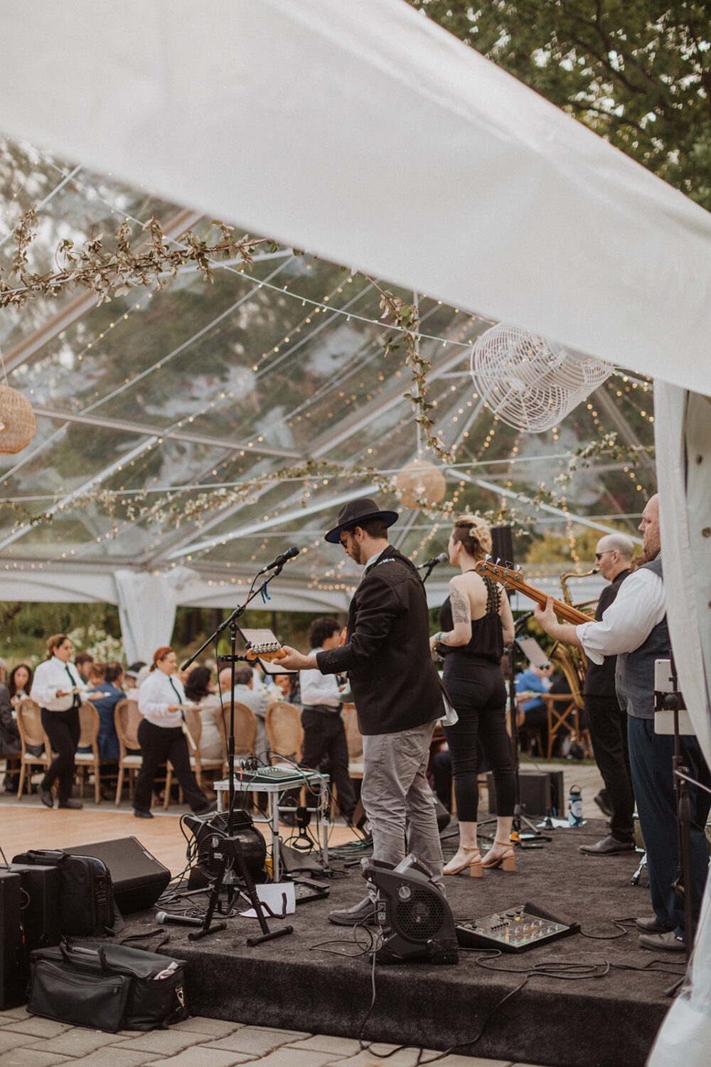 band performs during outdoor wedding with tent 