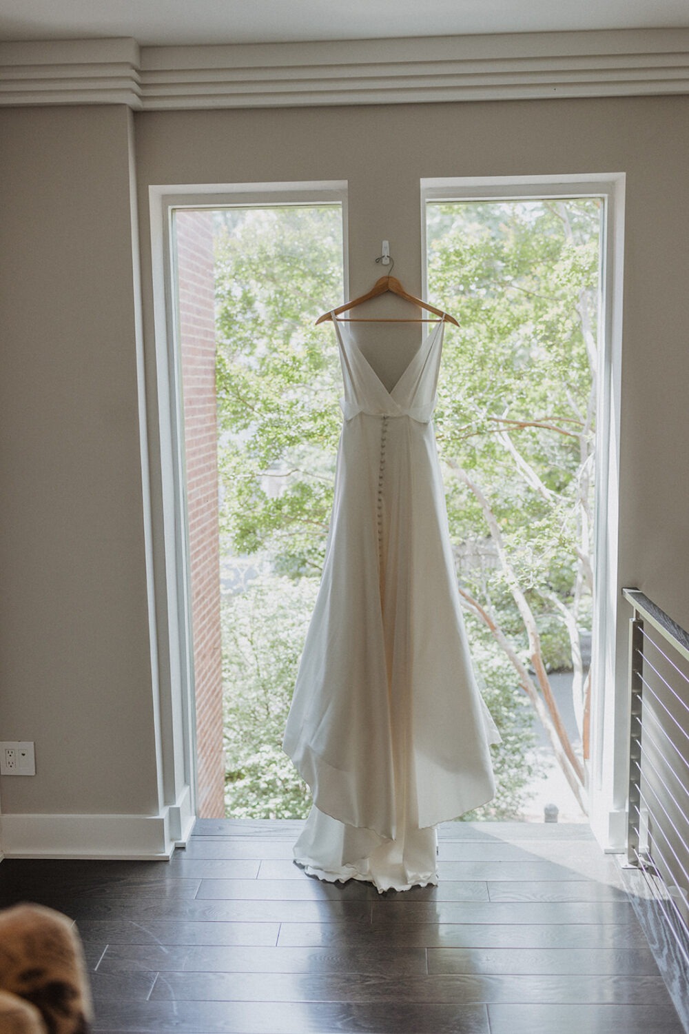 white wedding dress hangs on window