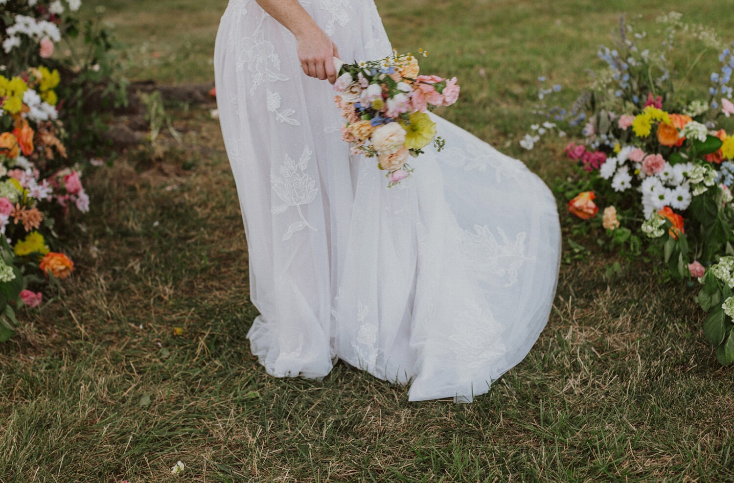 bride walks in garden holding wildflower wedding bouquet