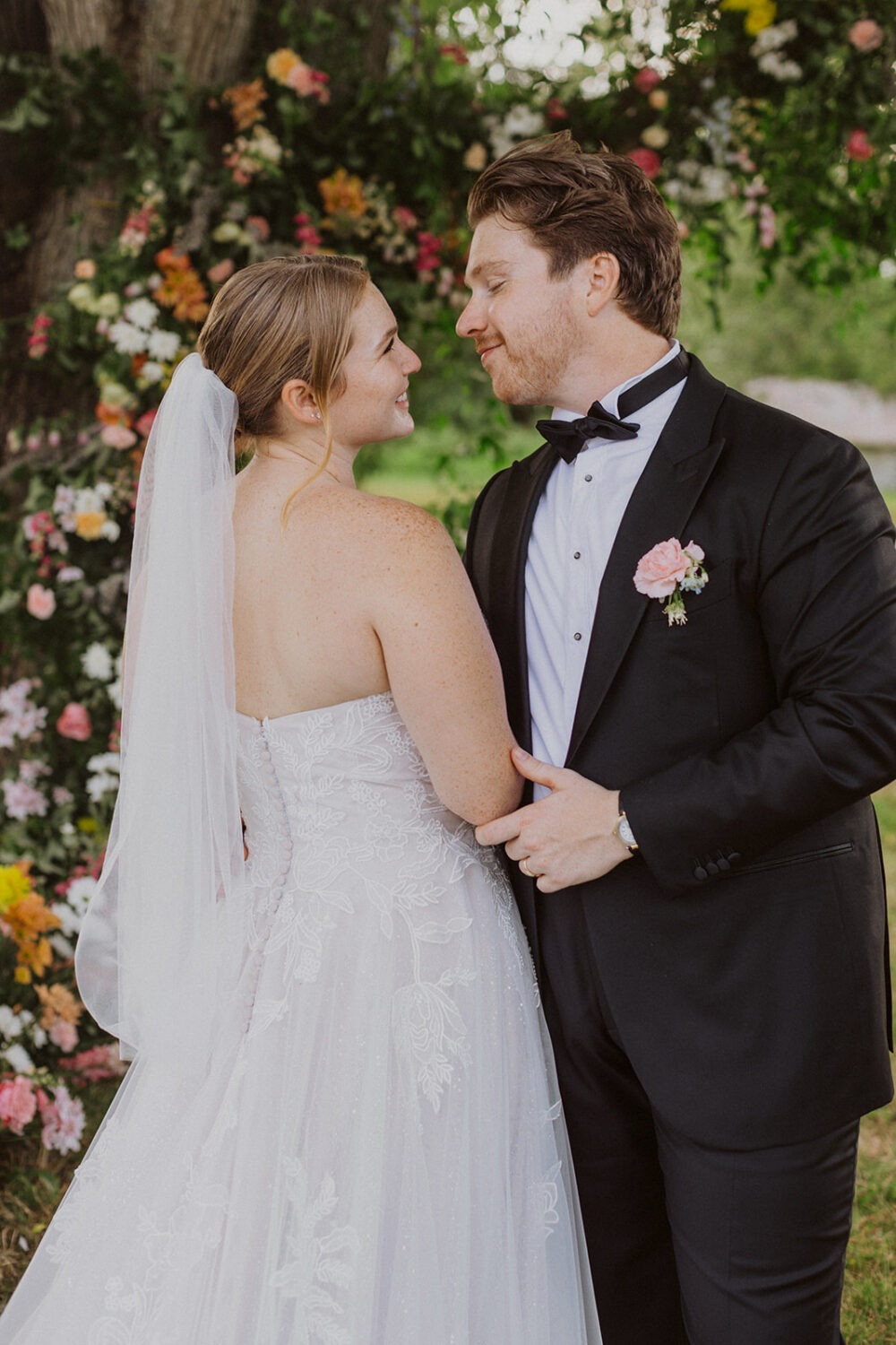 couple embraces surrounded by wedding florals