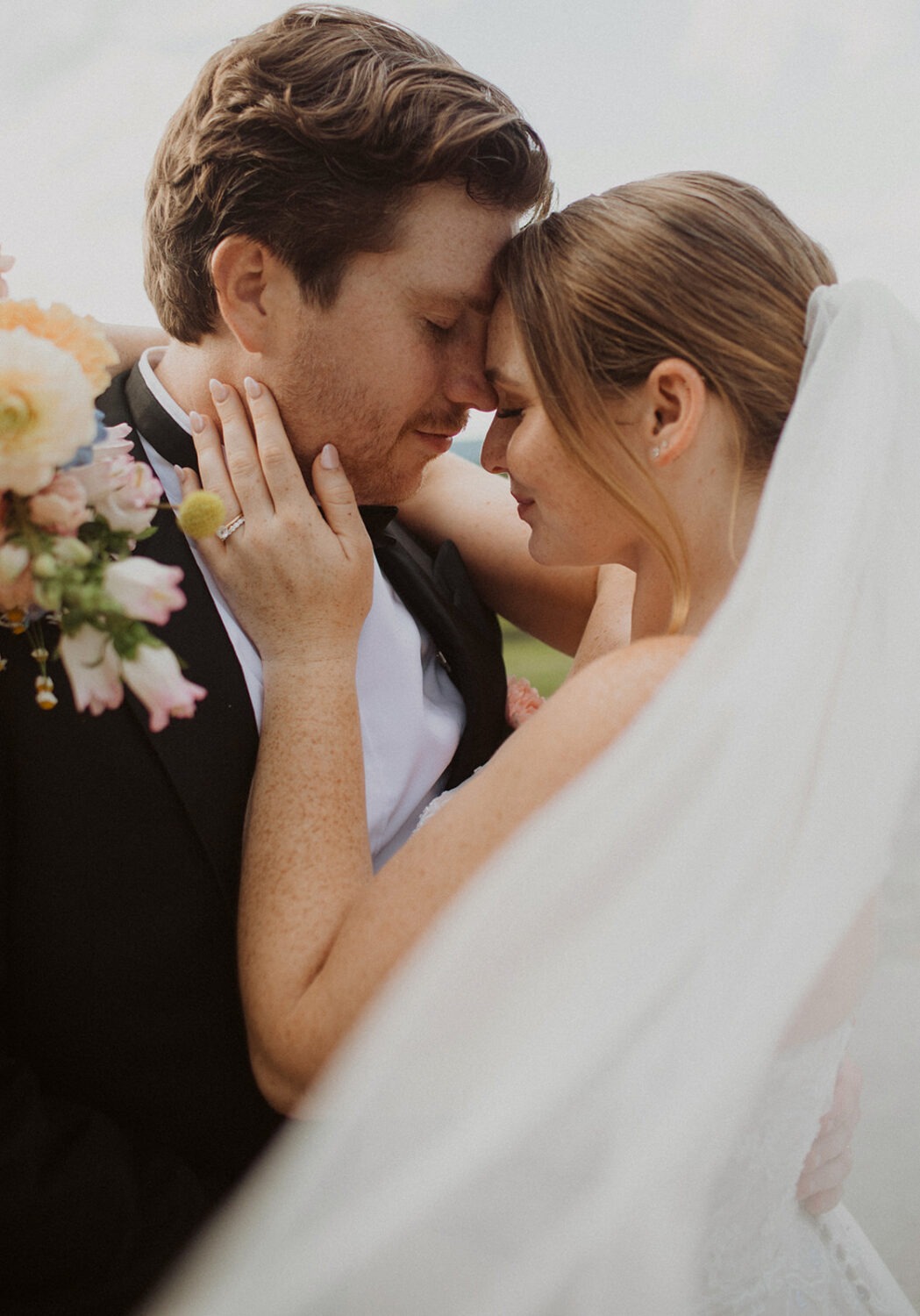 couple embraces under white veil