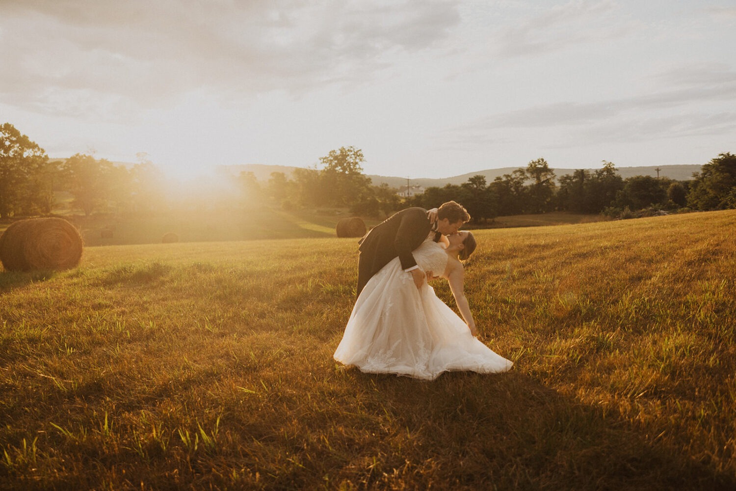 couple kisses in sunset field at outdoor wedding 