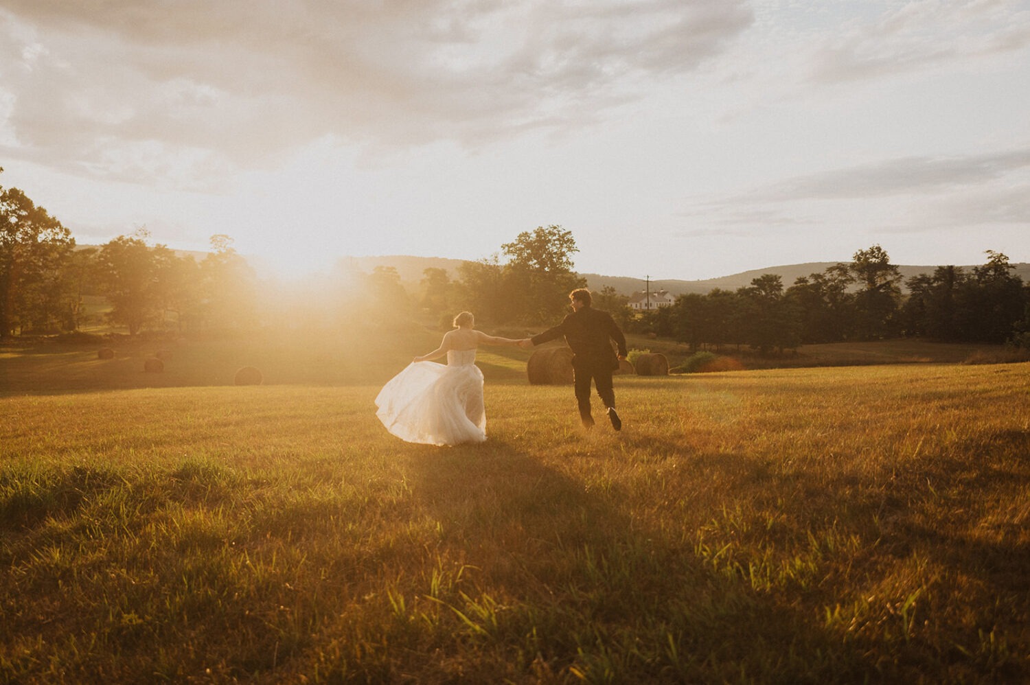 couple holds hands in field at The Manor at Airmont wedding