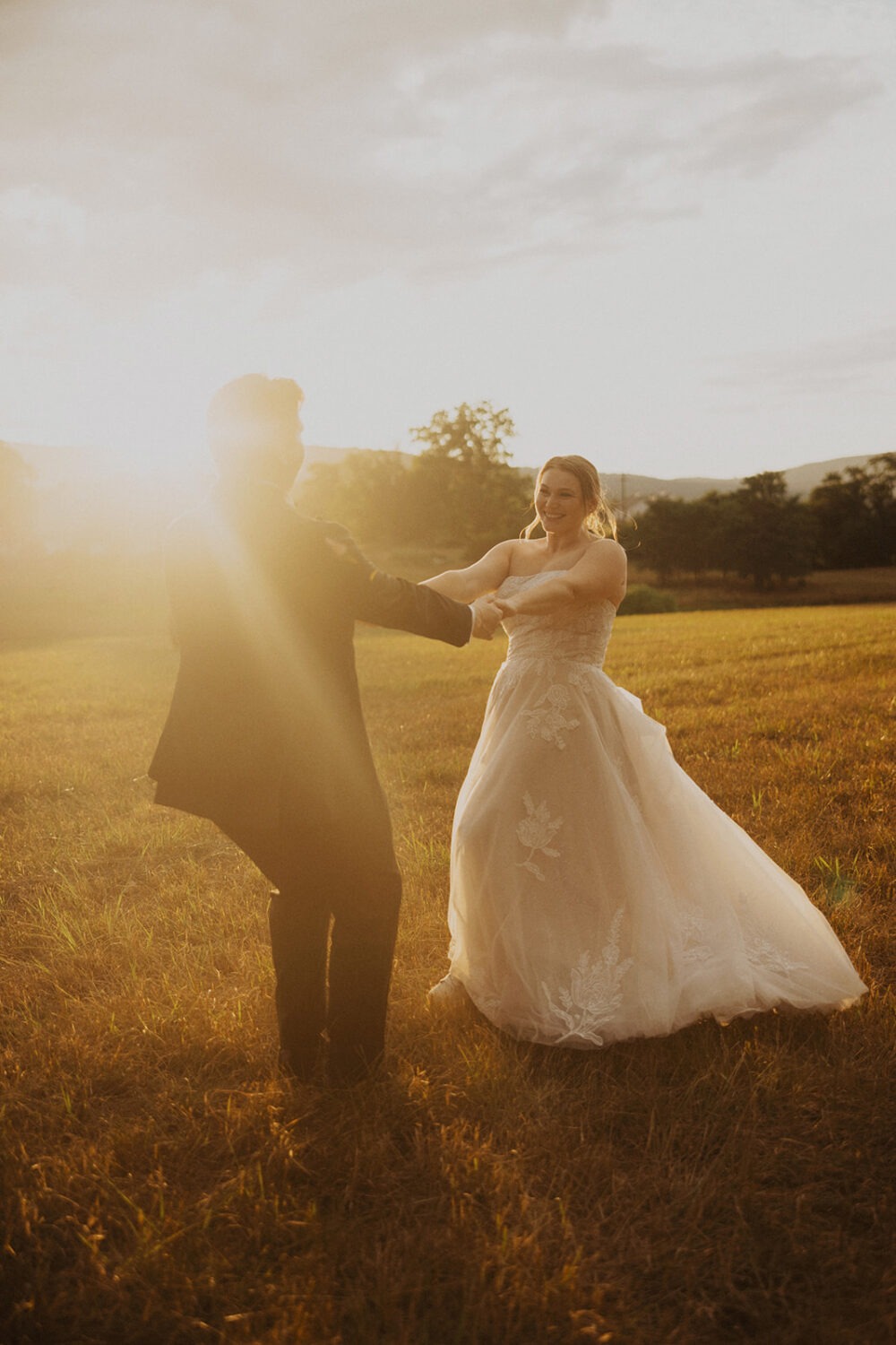 couple twirls at outdoor field sunset wedding venue