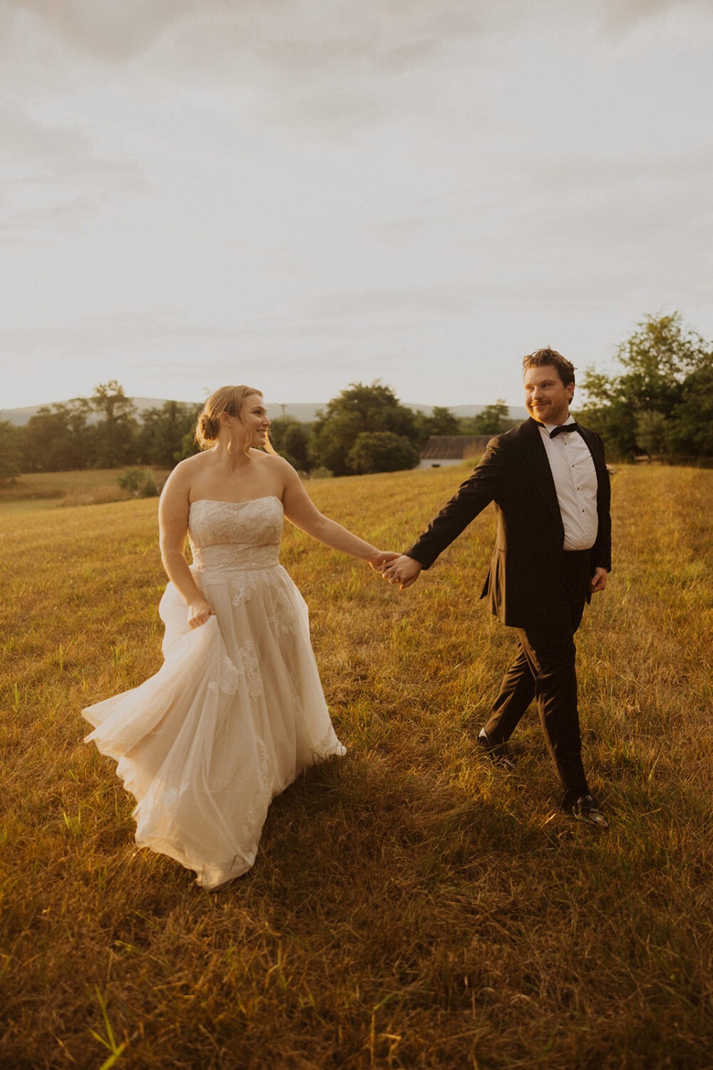 couple holds hands in field at The Manor at Airmont wedding