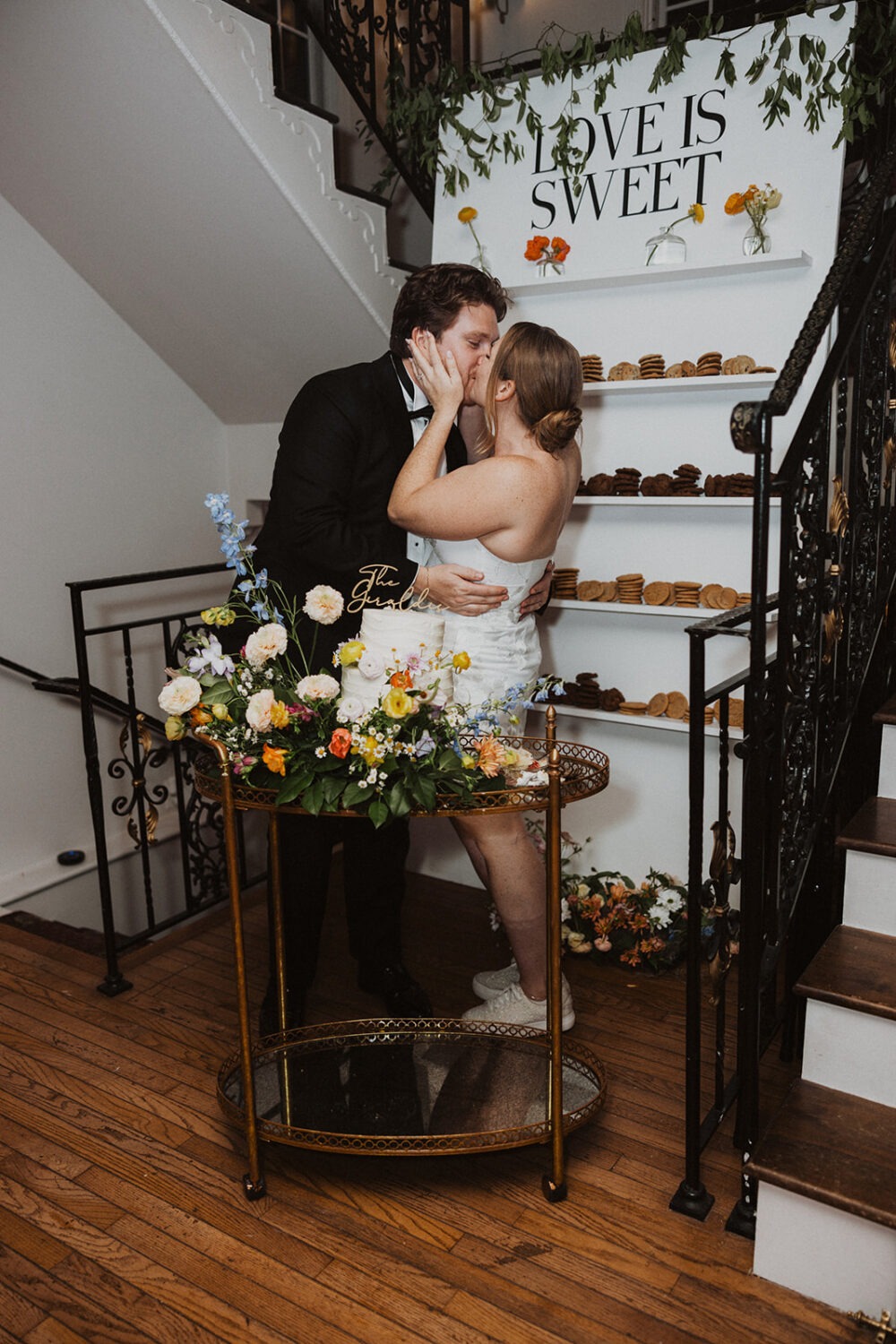 couple kisses while cutting wedding reception cake