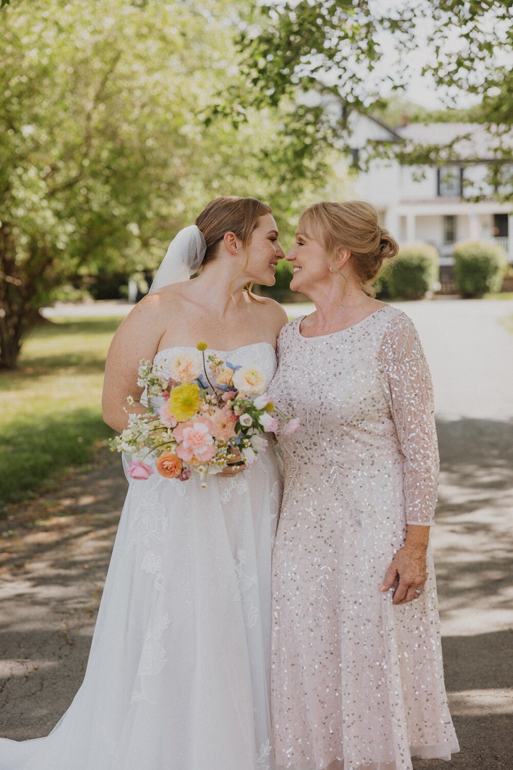 bride poses with mom holding wedding bouquet 