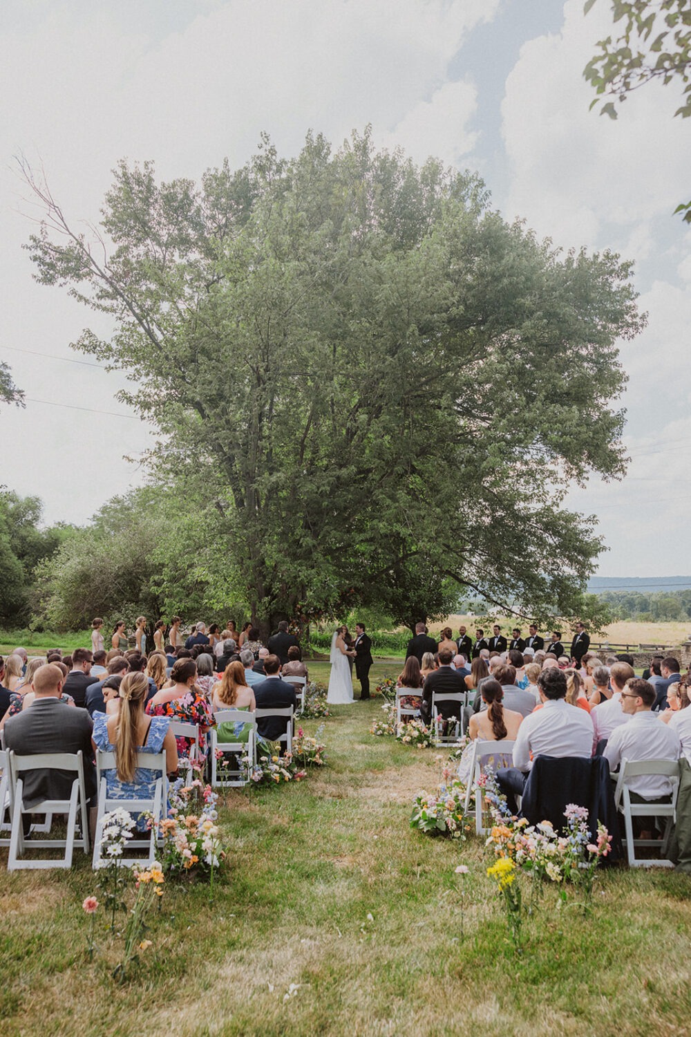 couple exchanges vows under tree  at The Manor at Airmont wedding