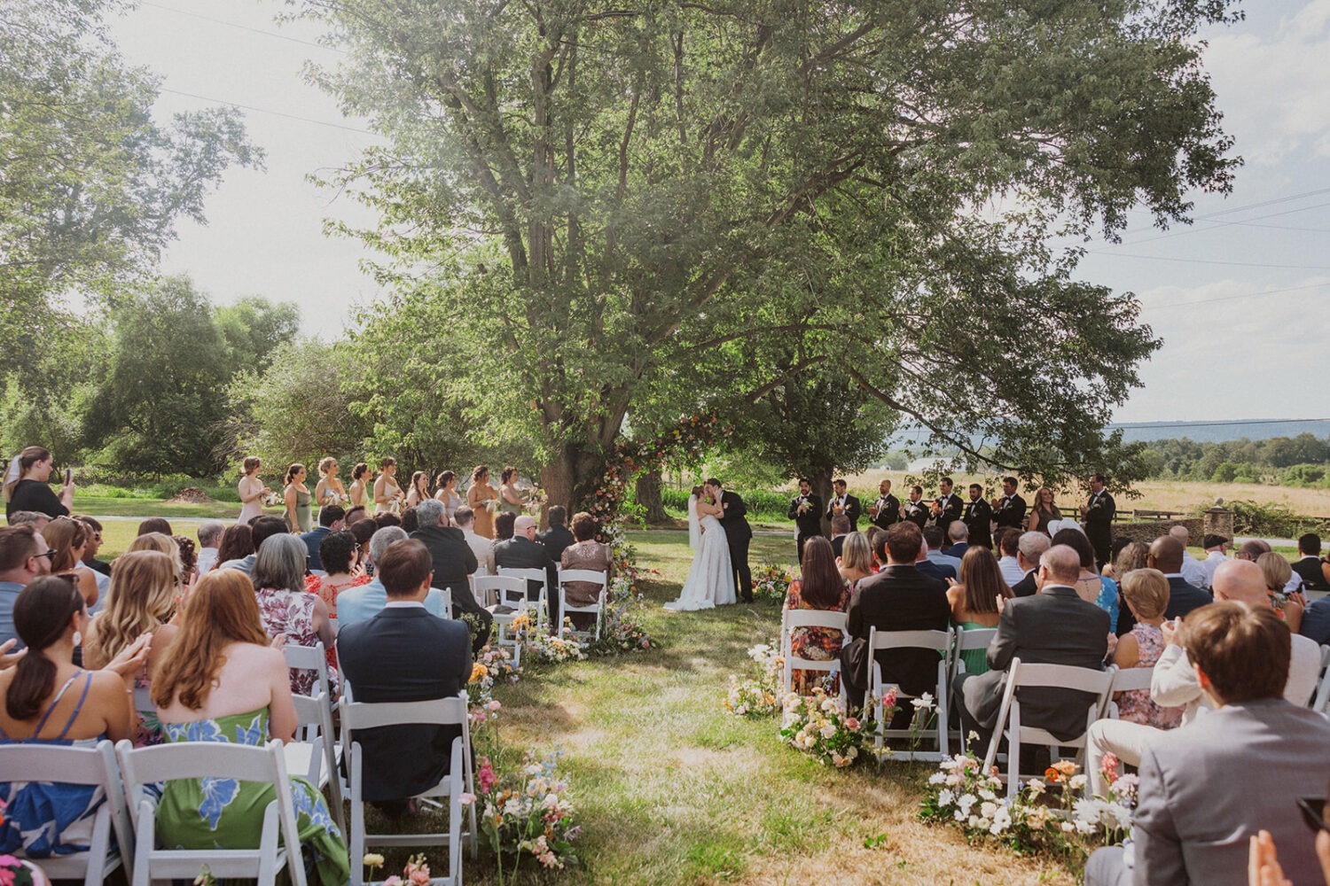 couple kisses under tree at The Manor at Airmont wedding ceremony