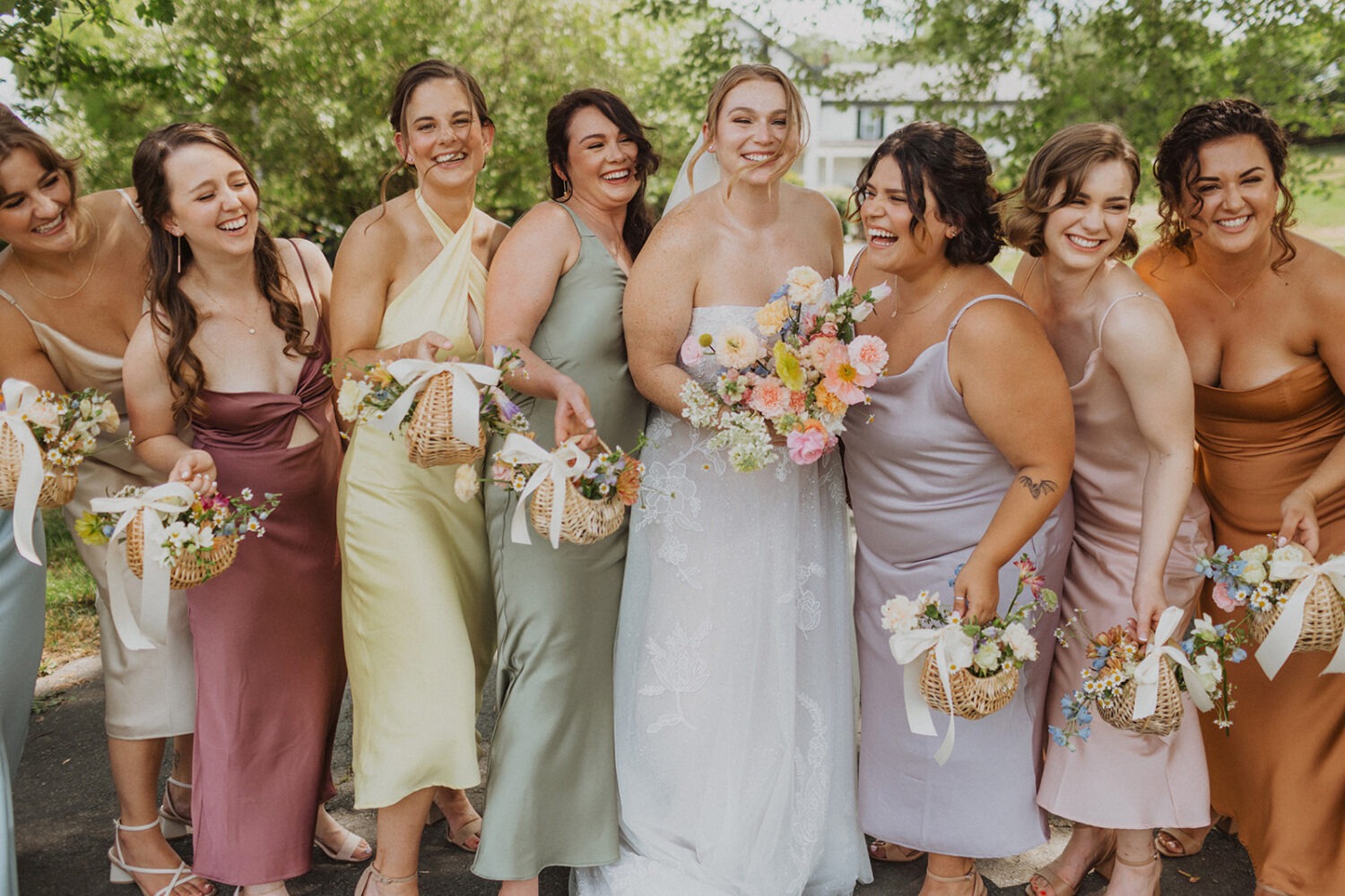 bride poses with bridesmaids holding bouquets in baskets