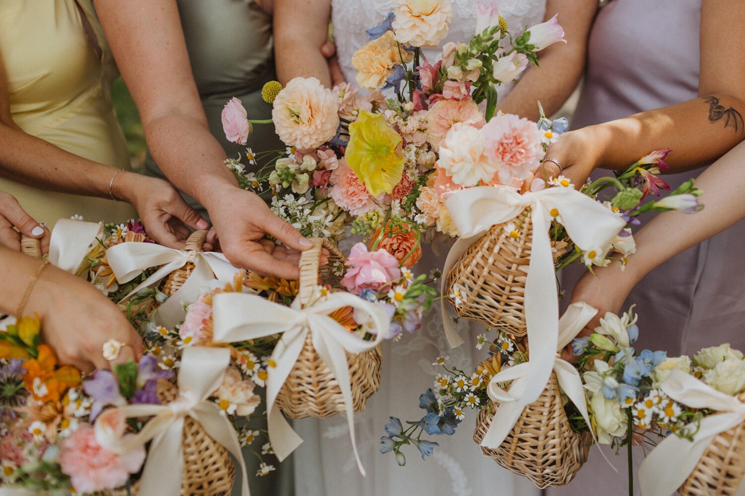 bride poses with bridesmaids holding bouquets in baskets