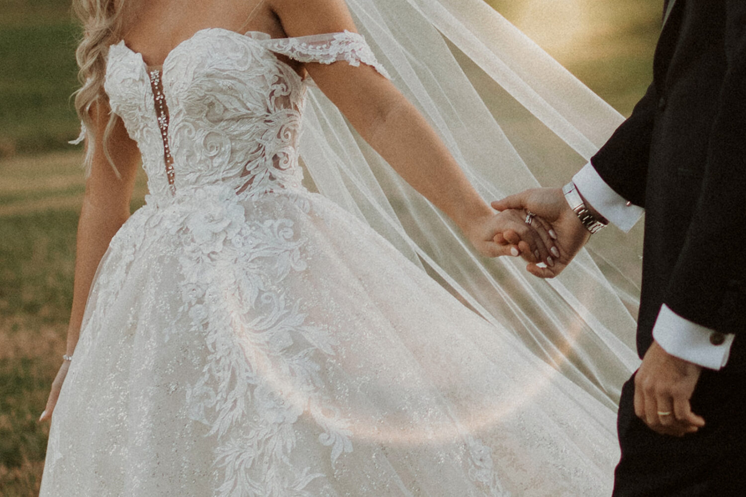 couple walks holding hands at outdoor sunset wedding 