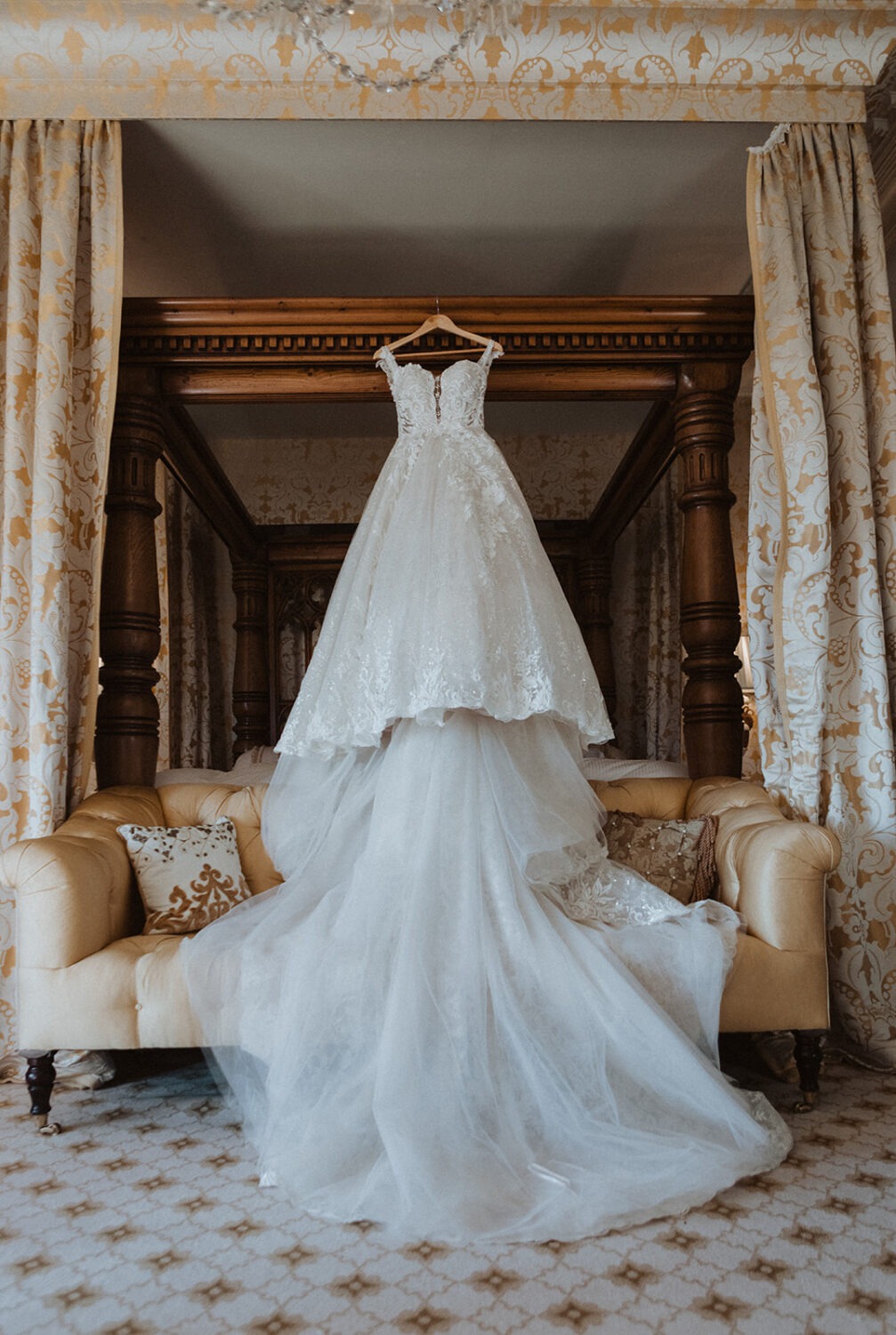 white wedding dress hangs off of bed