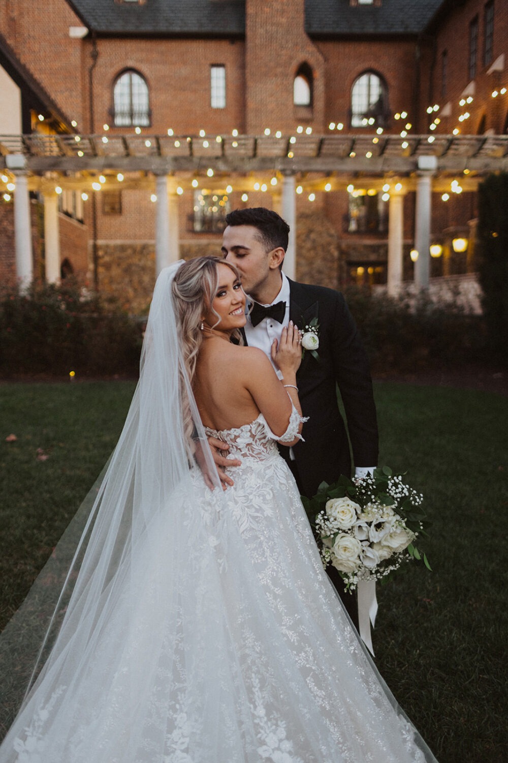 couple kisses under twinkle lights at Dover Hall Virginia wedding venue