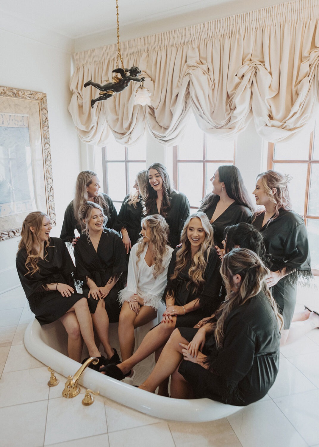 bride sits with bridesmaids in bridal suite tub