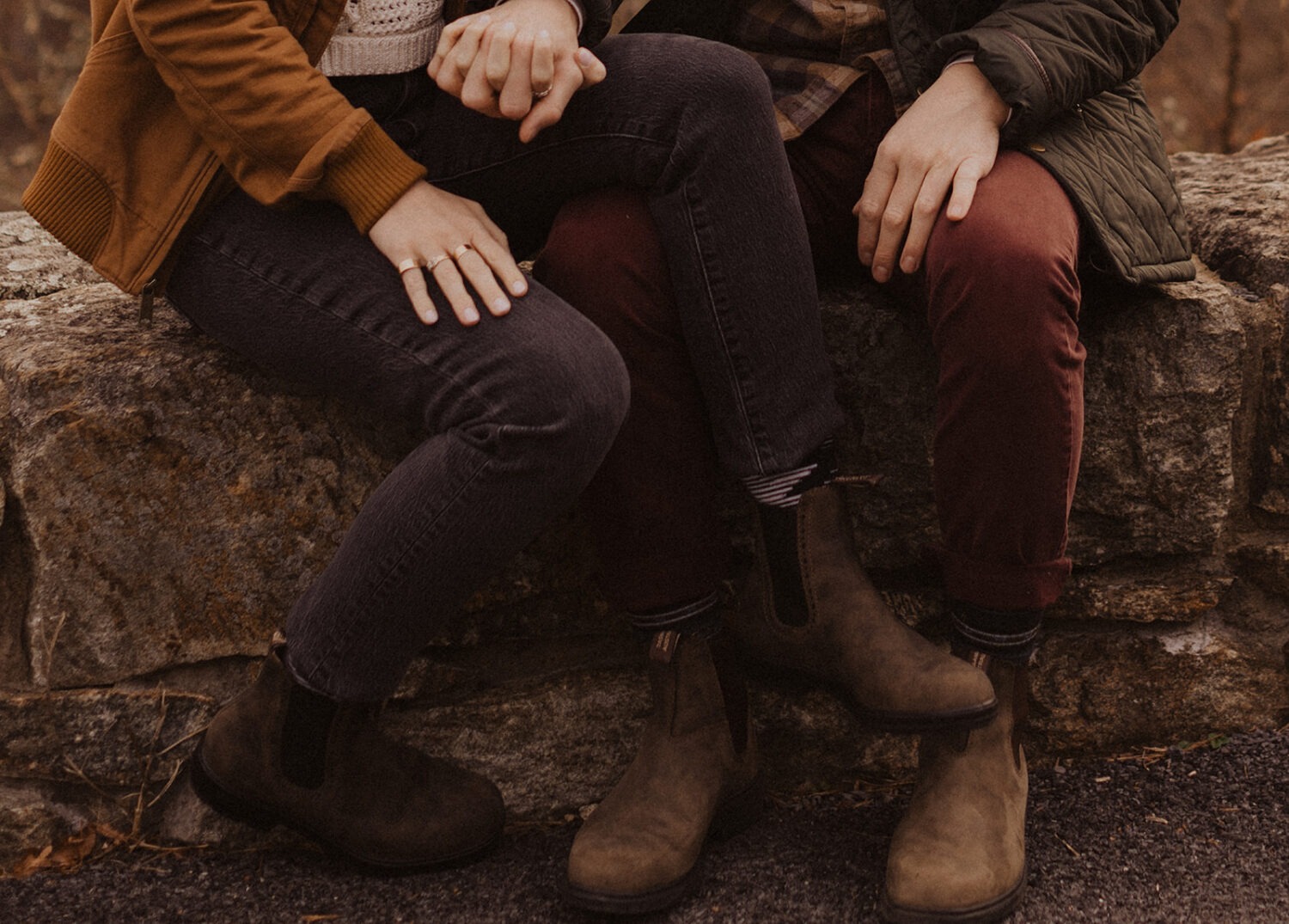 couple sits together in fall engagement outfits at outdoor session