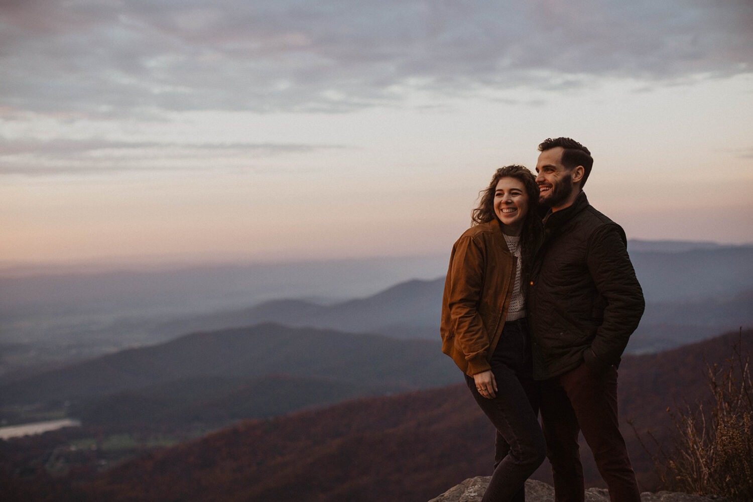 couple poses on overlook for fall engagement photos