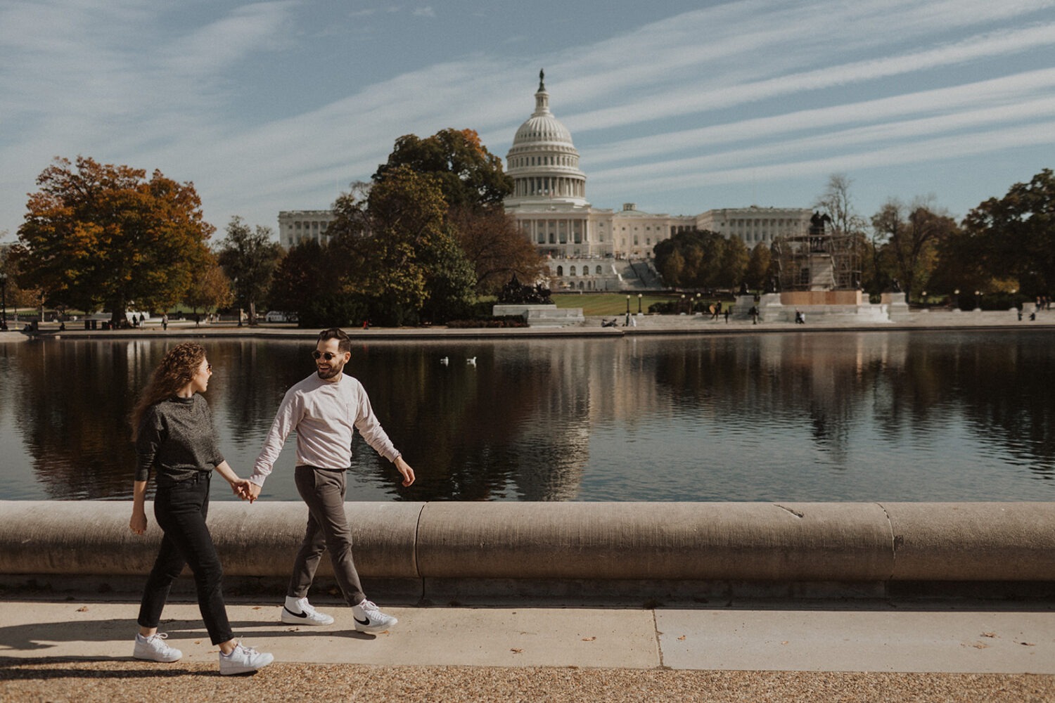 couple walks holding hands at DC National Mall engagement session