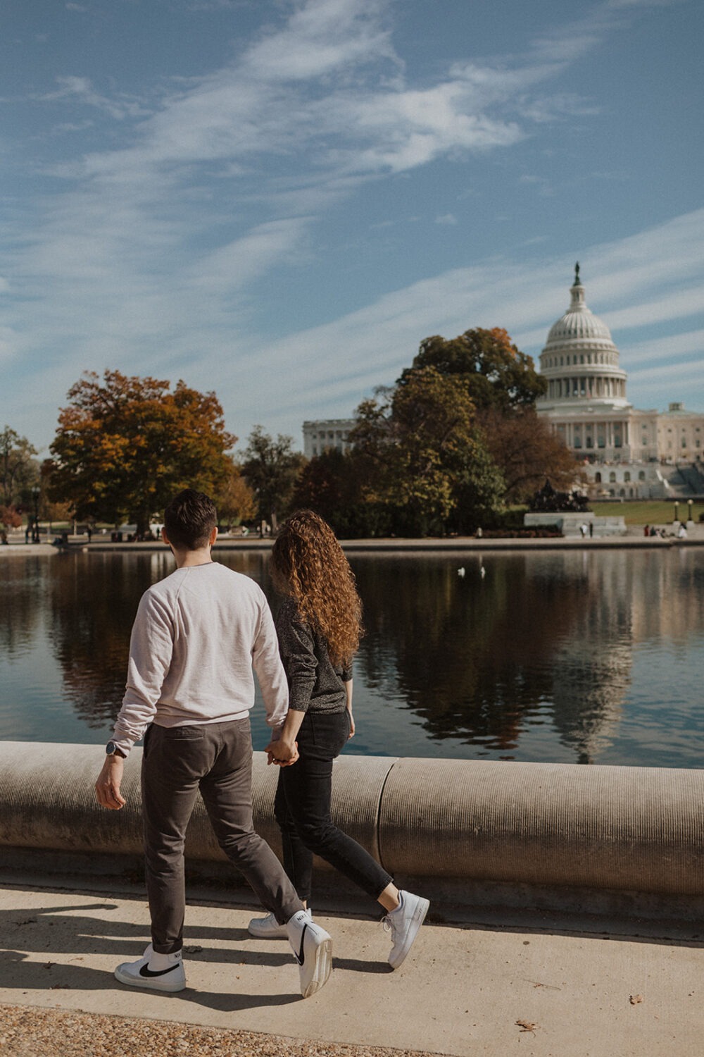 couple walks holding hands at DC National Mall engagement session