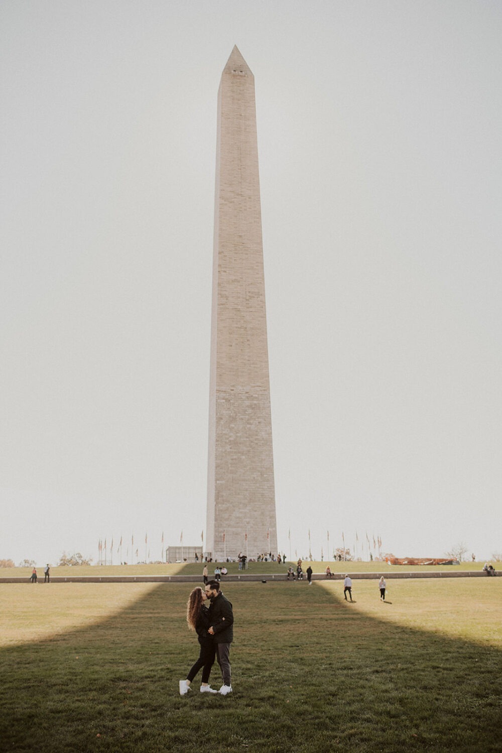 couple kisses in front of Washington Monument at engagement session