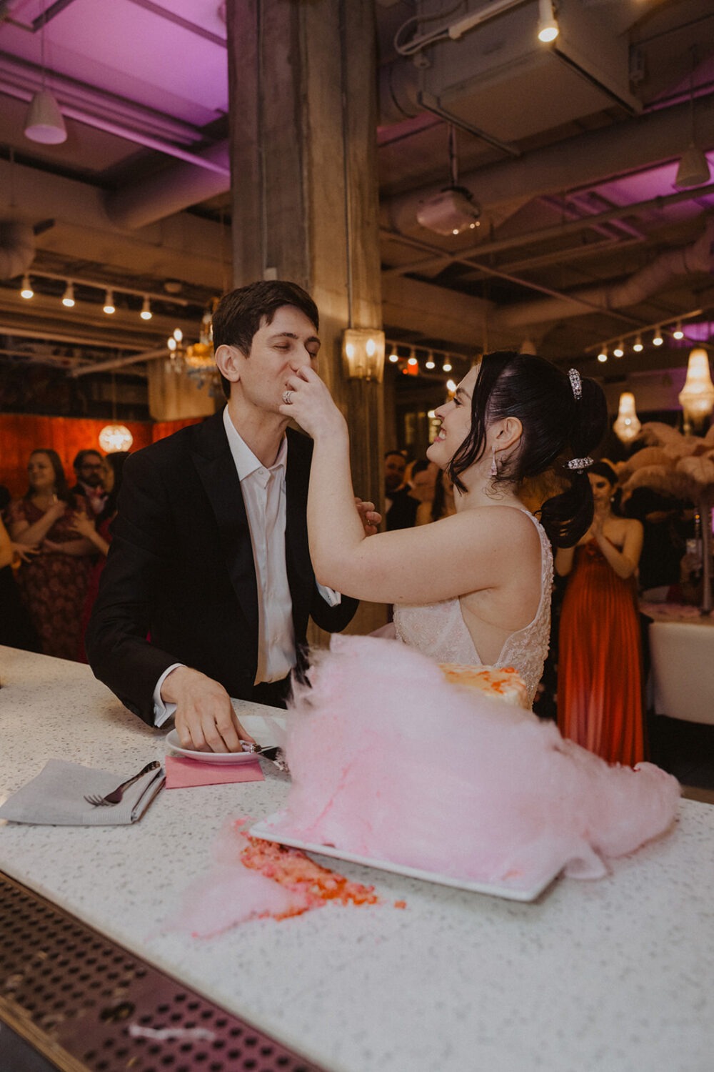 couple sharing cake with cotton candy during wedding reception