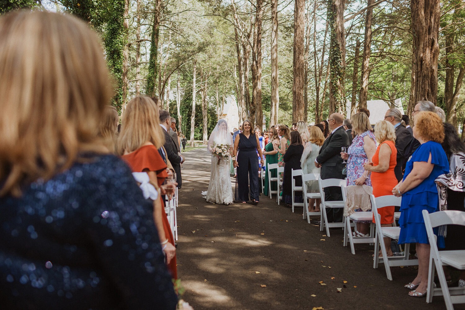 bride walks down aisle at outdoor wedding ceremony