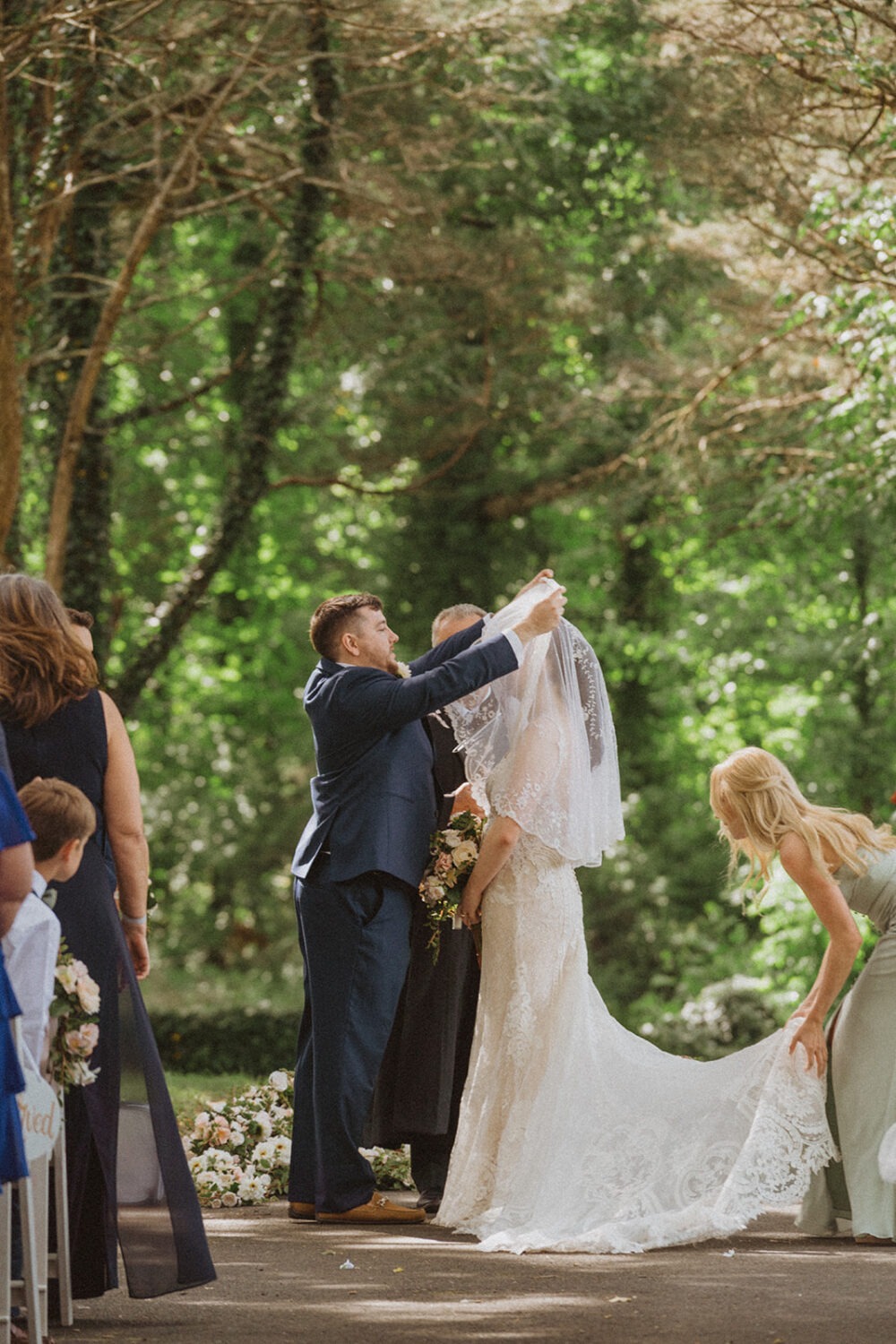 groom lifts veil at outdoor wedding ceremony