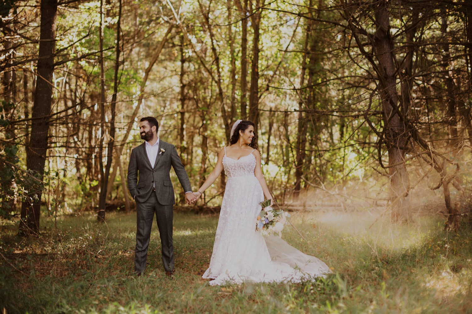 couple holds hands at sunset forest wedding 