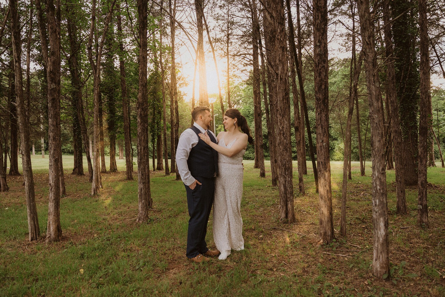 couple walks through forest at sunset