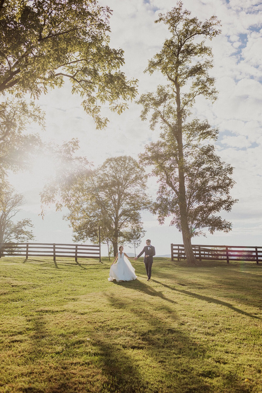 couple walks in meadow at sunset wedding