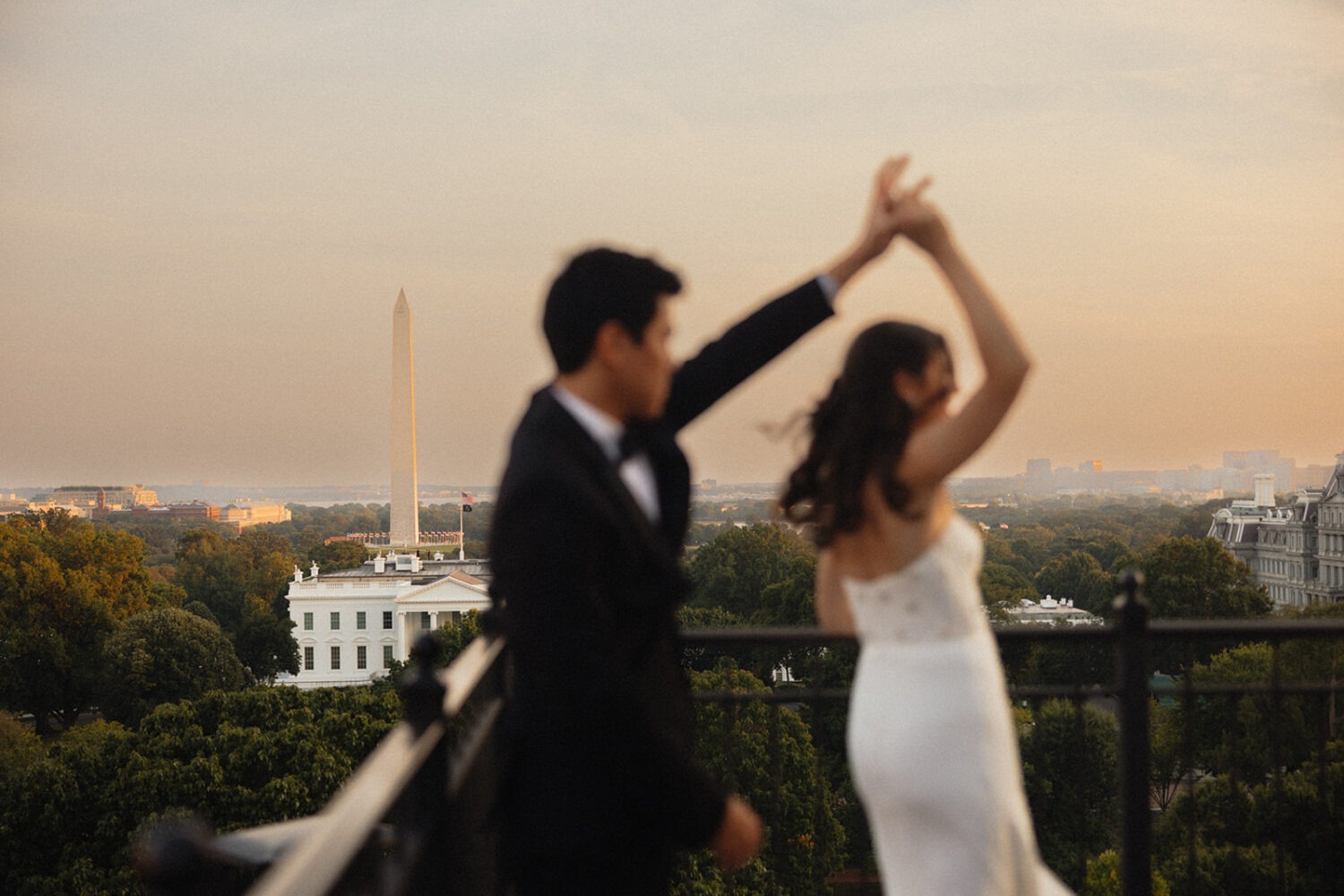 Bride and groom spinning on rooftop with Washington Monument In the background