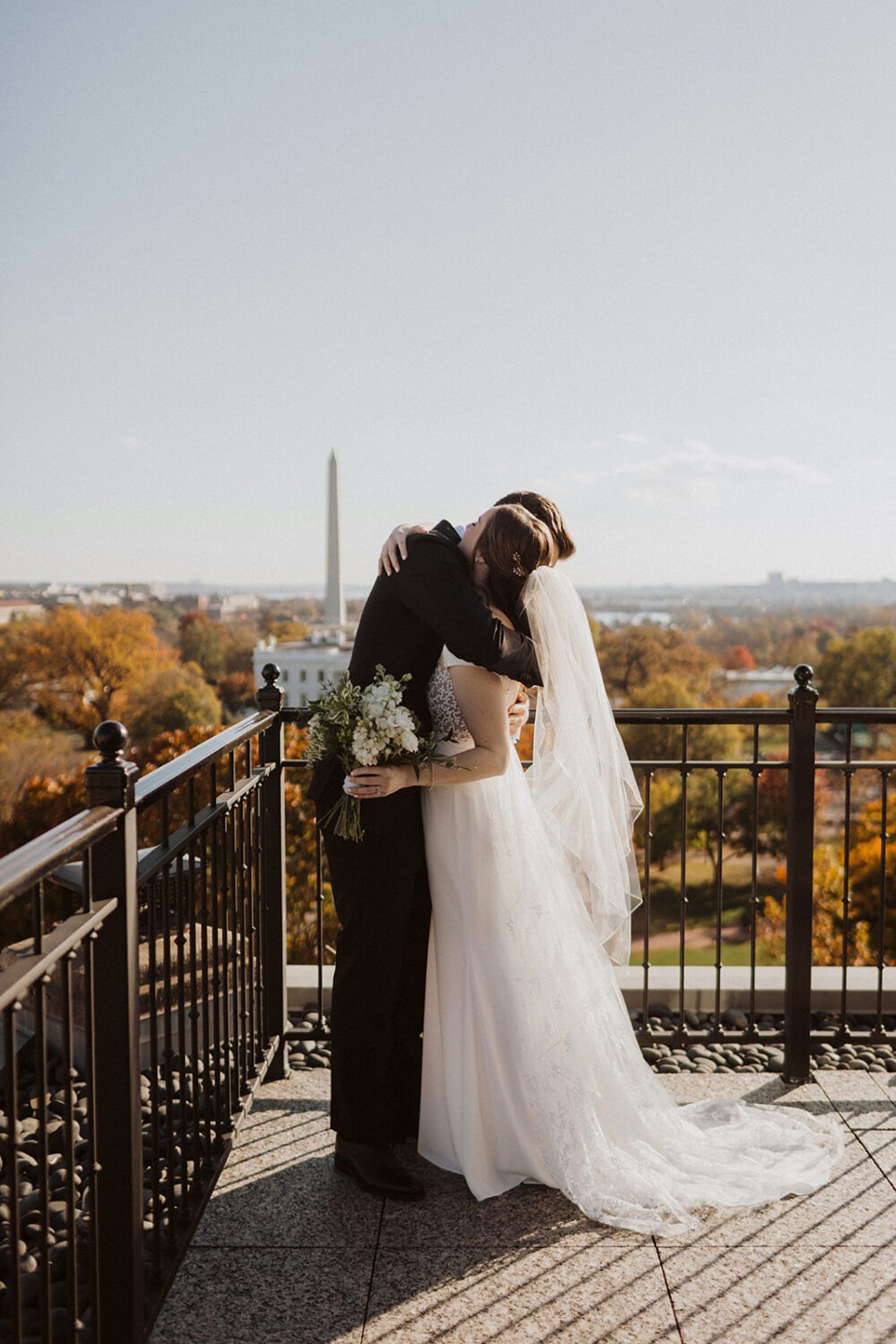 Bride and groom hugging on balcony.